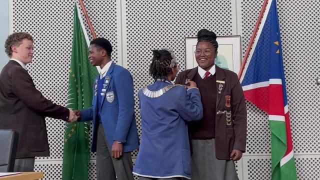 SWAKOPMUND, 27 August 2024 - Indila Abraham (R) has been elected as the new Swakopmund Junior Mayor. Here she receives her badge from outgoing junior mayor Berry Kawana while her deputy, Diego Nujoma (L) shakes the hand of outgoing deputy mayor Preston Husselmann. The two junior leaders were sworn in on Tuesday. (Photo by: Isabel Bento) NAMPA