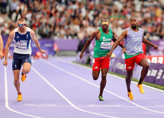 PARIS, 05 September 2024 – Namibia’s 2016 Paralympic Games gold medalist Ananias Shikongo and his guide Even Tjiuiju and French sprinter Timothee Adolphe (left) in action during the final of the men’s T11 100-meter race at the Stade de France during the Paris 2024 Paralympic Games. (Photo by: Hesron Kapanga) NAMPA