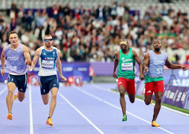 PARIS, 05 September 2024 – Namibia’s 2016 Paralympic Games gold medalist Ananias Shikongo and his guide Even Tjiuiju and French sprinter Timothee Adolphe and his guide Charles Renard (left) in action during the final of the men’s T11 100-meter race at the Stade de France during the Paris 2024 Paralympic Games. (Photo by: Hesron Kapanga) NAMPA