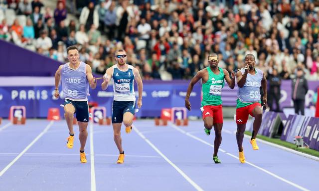 PARIS, 05 September 2024 – Namibia’s 2016 Paralympic Games gold medalist Ananias Shikongo and his guide Even Tjiuiju and French sprinter Timothee Adolphe and his guide Charles Renard (left) in action during the final of the men’s T11 100-meter race at the Stade de France during the Paris 2024 Paralympic Games. (Photo by: Hesron Kapanga) NAMPA