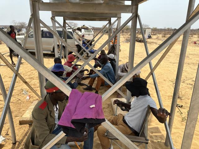 GAM, 21 September 2024 - A section of community members forming part of the latest Namibian returnees from Botswana take cover from the sun under the stand of a water storage tank. (Photo by: Josephina Simeon) NAMPA