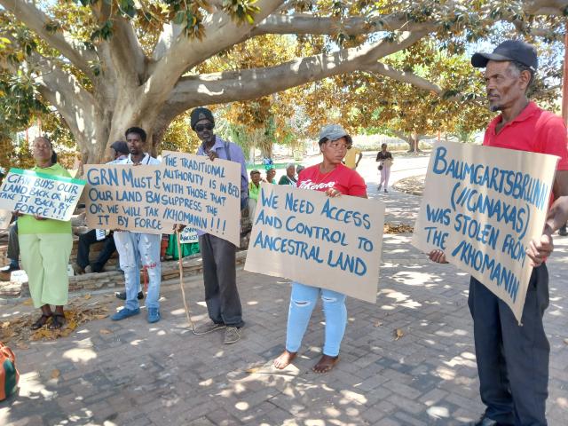 /Khomanin community members hold posters at a demonstration in Zoo Park, demanding recognition of ancestral rights. (Photo by: Melissa MC //Hoebes) NAMPA