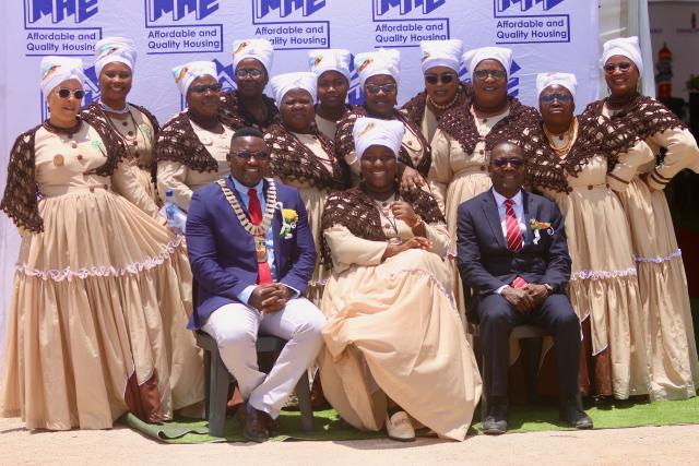 SWAKOPMUND, 13 December 2024 - Minister of Urban and Rural Development, Erastus Uutoni (seated right) and Mayor of Swakopmund Blasius Goraseb flanked by the DRC Informal Settlement Choir during the launch of the Informal Settlement Upgrade Project in Swakopmund. The project is aimed at constructing over 800 houses in the DRC informal settlement. (Photo by: Hesron Kapanga) NAMPA