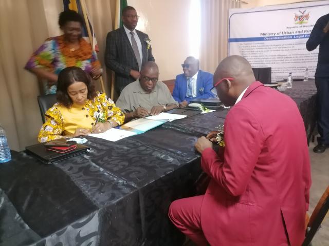 OTJIWARONGO, 22 October 2025 - Signing off on Wednesday at Otjiwarongo to decentralise functions of the agriculture's extension and engineering services to the 14 regional councils by Minister Inge Zaamwani (left), while Otjozondjupa Regional Council chairperson, Johannes Hausiku (right) signs on behalf of the Otjozondjupa Regional Council and Urban and Rural Development Minister, James Sankwasa signs as a witness hence regional councils fall under his ministry. (Photo by:Mulisa Simiyasa) NAMPA 