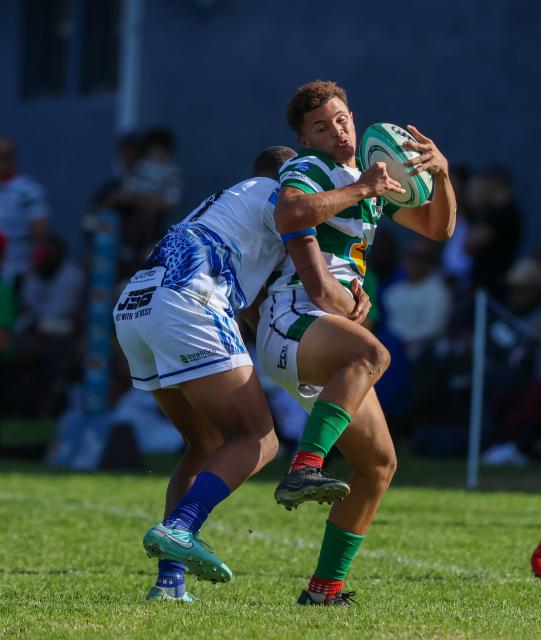 WINDHOEK, 18 April 2026 - A Western Suburbs player (in green and white) takes on Grootfontein opponents (in blue and white) during their Round Two clash of the Namibia Rugby Union Premier League at Suburbs Park in Khomasdal. (Photo by: Hesron Kapanga) NAMPA
