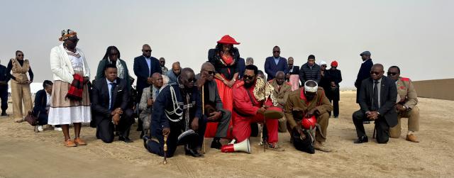 SWAKOPMUND, 28 May 2026 - Chiefs of the Zeraeua and !Oe-ǂGan Traditional Authorities Ombara Manase Christian Zeraeua and Gaob Immanuel ǂNu-axa ǃGâseb (l), Chairperson of the Genocide Committee in Erongo Uahimisa Kaapehi (m) and other political and traditional leaders kneel at the entrance of the Swakopmund Memorial Park to seek for permission from the ancestors before entering the cemetery, during the Ovaherero and Nama Genocide. (Photo by: Isabel Bento) NAMPA