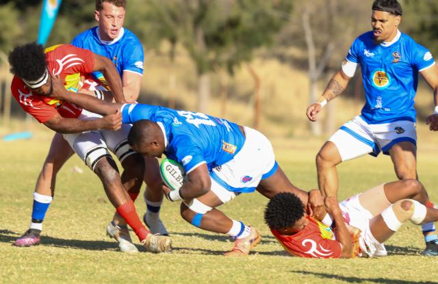 WINDHOEK, 20 June 2026 - Coastal outfit Kudus Rugby Club centre Tonderai Ndudzo in (blue with a ball) while in action against UNAM (red & white) at the UNAM Stadium on Saturday, during Round Six Namibia Rugby Union (NRU) Premier League clash the match ended 41-27 in favour of Kudus. (Photo by: Hesron Kapanga) NAMPA