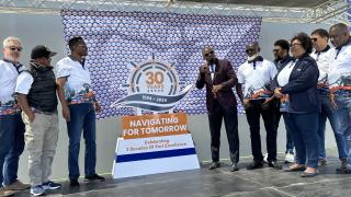 WALVIS BAY, 30 September 2024 - Namport Chief Executive Officer Andrew Kanime unveiling the port’s new logo at its 30th anniversary celebration at Walvis Bay. Kanime is photographed with some of the company’s longest serving employees. (Photo by: Isabel Bento) NAMPA