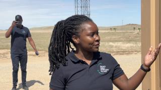 DAURES, 29 April 2025 - Renewable Energy Analyst Aina Kauluma explains DGHV’s living laboratory for renewable energy education. The village’s demo site, features three 3.6 kW wind turbines, a 2.75 kW solar array, batteries, and a 3 kW electrolyser. (Photo by: Isabel Bento) NAMPA