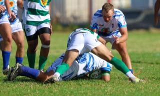 WINDHOEK, 18 April 2026 - A Western Suburbs player (in green and white) takes on Grootfontein opponents (in blue and white) during their Round Two clash of the Namibia Rugby Union Premier League at Suburbs Park in Khomasdal. (Photo by: Hesron Kapanga) NAMPA