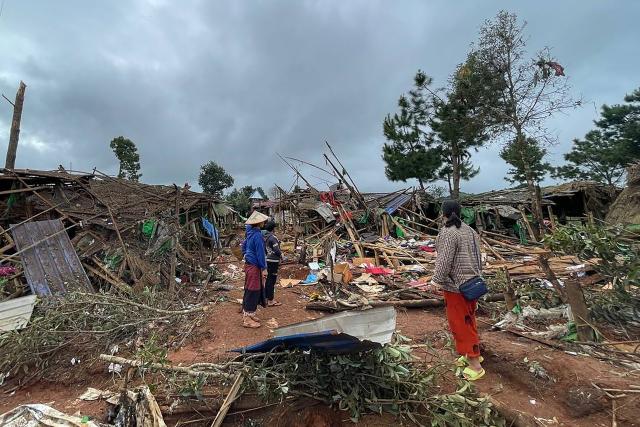 People stand next to destroyed shelters at a camp for internally displaced people following an air strike near Pekon township in Myanmar's south Shan state on September 6, 2024. (Photo by AFP)