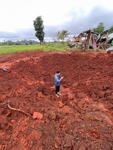 A man stands in a bomb crater at a camp for internally displaced people after air strikes near Pekon township in Myanmar's south Shan state on September 6, 2024. (Photo by AFP)