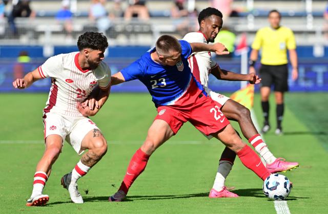 Canada's midfielder Jonathan Osorio (Lt) and Canada's midfielder Ali Ahmed (R) double-team United States' defender Kristoffer Lund in the second half of an international friendly football match between USA and Canada at Children's Mercy Park in Kansas City, Kansas, on September 7, 2024. (Photo by Tim Vizer / AFP)