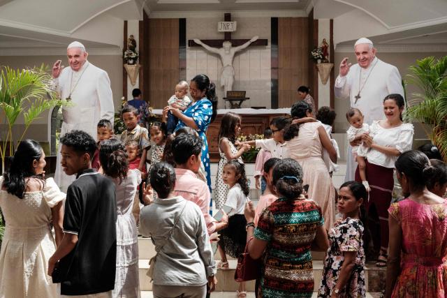 Catholic faithful take pictures with installed two life-size boards of Pope Francis after a Sunday mass at the Church of Saint Anthony of Motael ahead of Pope Francis' visit in Dili on September 8, 2024. (Photo by Yasuyoshi CHIBA / AFP)