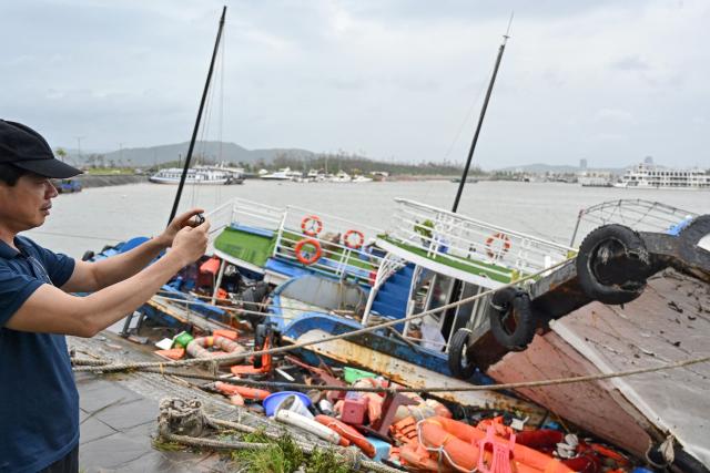 A man take a photo of boats damaged after Super Typhoon Yagi hit Ha Long bay, in Quang Ninh province, on September 8, 2024. Super Typhoon Yagi uproots thousands of trees, sweeps ships and boats out to sea and rips roofs off houses in northern Vietnam, after leaving a trail of destruction in southern China and the Philippines. (Photo by Nhac NGUYEN / AFP)