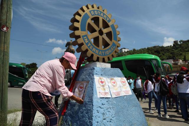 A woman pastes posters with slogans calling for justice on a Rotary Club monument as students from the Ayotzinapa normal school prepare to march in the city of Chilpancingo, Guerrero State, Mexico, on September 18, 2024, as part of the activities carried out to commemorate and demand justice for the disappearance of the 43 normal students. Next September 26 marks 10 years since the forced disappearance of 43 students from the Ayotzinapa Rural Normal School. (Photo by Franyeli GARCIA / AFP)