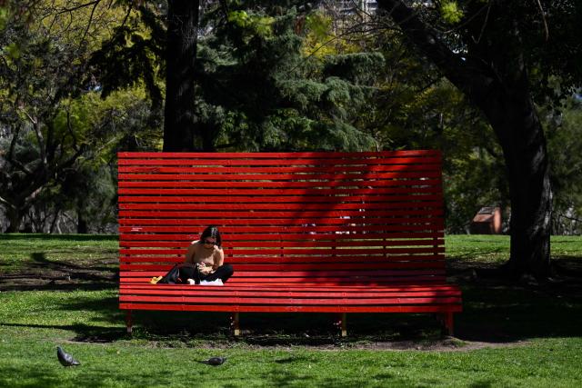 A woman eats sitting on a giant chair in Las Heras Park in Buenos Aires on September 20, 2024. (Photo by LUIS ROBAYO / AFP)