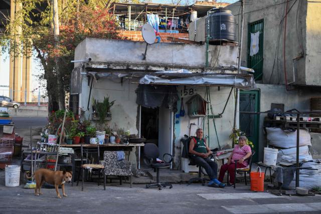 A couple is photographed in front of their house in the La Boca neighborhood in Buenos Aires on September 20, 2024. (Photo by LUIS ROBAYO / AFP)