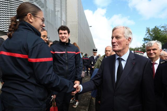 French Prime Minister Michel Barnier shakes hands with firefighters as he attends the 130th "Congres National des Sapeurs-Pompiers de France" (French firefighters congress), at the Parc des Expositions in Macon, central eastern France, on September 28, 2024. (Photo by Alex MARTIN / AFP)