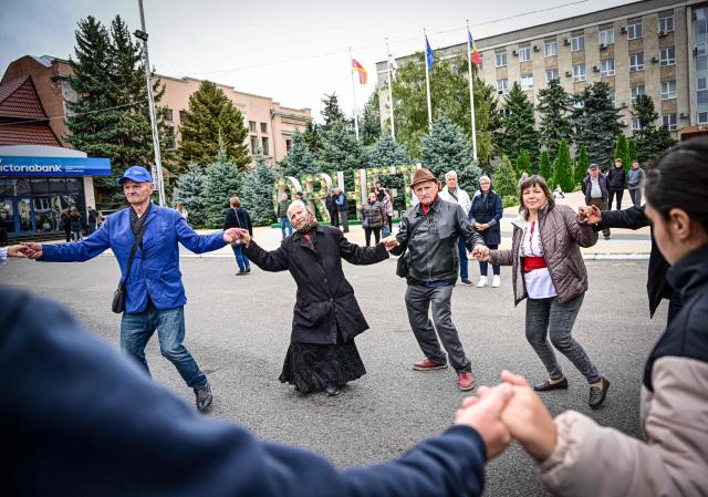 People dance during a wine festival in Orhei, central Moldova, on October 12, 2024. With Moldova's presidential elections and referendum on joining the EU fast approaching, the eastern European country's authorities fear up to a quarter of the ballots could be compromised by Russia. (Photo by Daniel MIHAILESCU / AFP)