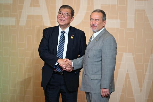 Peru's Minister of Foreign Affairs Elmer Schialer (R) greets Japan's Prime Minister Shigeru Ishiba upon his arrival at the APEC Economic Leaders’ Meeting (AELM) at the Convention Centre in Lima, on November 16, 2024. (Photo by Luis ACOSTA / AFP)