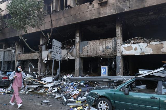 A woman walks past the debris of a building, targeted in an Israeli airstrike the previous day, in Beirut’s Mar Elias Street on November 18, 2024, amid the ongoing war between Israel and Hezbollah. (Photo by ANWAR AMRO / AFP)