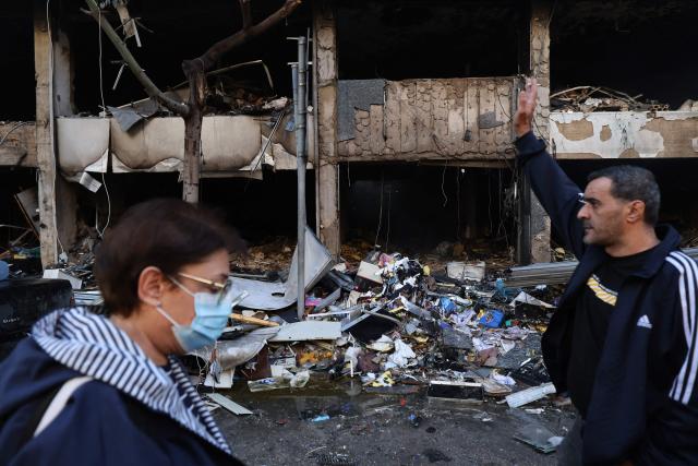 People inspect the damage to a building, targeted in an Israeli airstrike the previous day, in Beirut’s Mar Elias Street on November 18, 2024, amid the ongoing war between Israel and Hezbollah. (Photo by ANWAR AMRO / AFP)