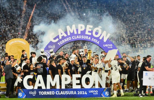 Olimpia's players celebrate with the trophy after winning the Paraguayan football league final football match between Olimpia and Nacional at Defensores del Chaco Stadium in Asuncion on November 24, 2024. (Photo by Daniel Duarte / AFP)