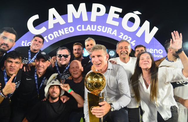 Olimpia's head coach Argentine Martin Palermo (C) celebrates with the trophy after winning the Paraguayan football league final football match between Olimpia and Nacional at Defensores del Chaco Stadium in Asuncion on November 24, 2024. (Photo by Daniel Duarte / AFP)