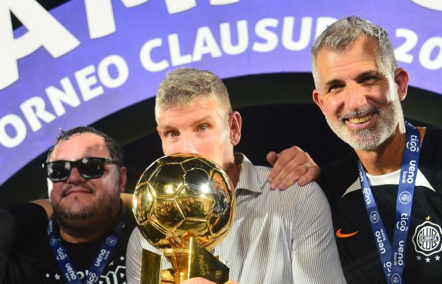 Olimpia's head coach Argentine Martin Palermo (C) celebrates with the trophy after winning the Paraguayan football league final football match between Olimpia and Nacional at Defensores del Chaco Stadium in Asuncion on November 24, 2024. (Photo by Daniel Duarte / AFP)