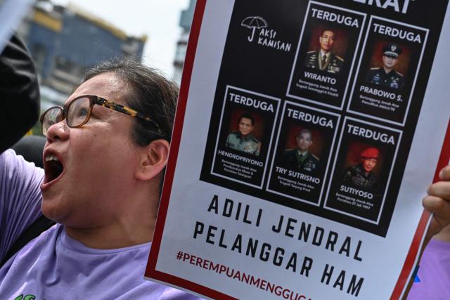 An activist holds a placard that reads "trial for human rights-violating generals" during a street protest on the International Day for the Elimination of Violence Against Women, in Jakarta on November 25, 2024. (Photo by BAY ISMOYO / AFP)