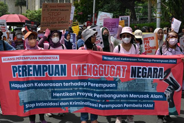 Activists hold a banner against violence against women, halt environmentally destructive development projects, and stop the intimidation and criminalization of women human rights activists during a street protest on the International Day for the Elimination of Violence Against Women, in Jakarta on November 25, 2024. (Photo by BAY ISMOYO / AFP)