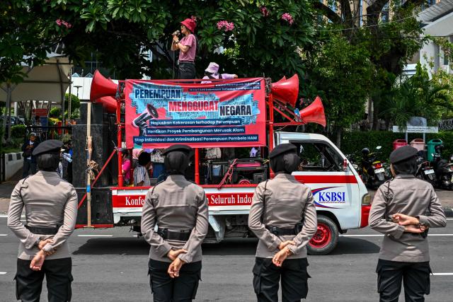 Policewomen keep watch as activists take part in a street protest on the International Day for the Elimination of Violence Against Women, in Jakarta on November 25, 2024. (Photo by BAY ISMOYO / AFP)