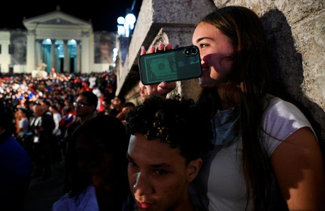 A young woman takes pictures with her cell phone during the vigil for the 8th anniversary of Cuban late leader Fidel Castro's physical disappearance in Havana on November 25, 2024. (Photo by YAMIL LAGE / AFP)