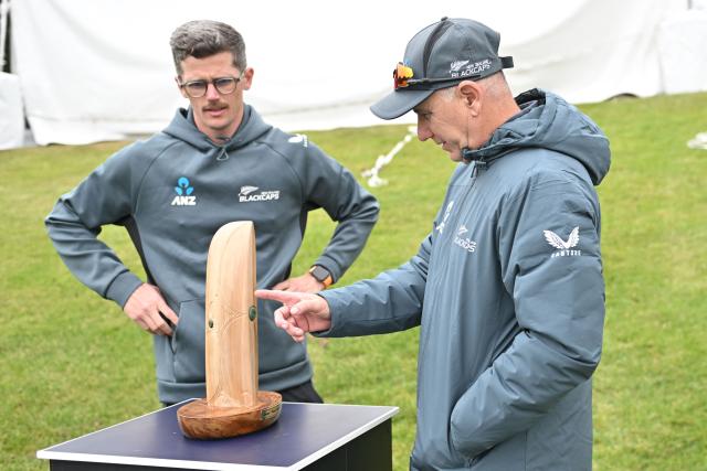 New Zealand's coach Gary Stead (R) inspects the Crowe-Thorpe trophy, honoring late New Zealand's Martin Crowe and England's Graham Thorpe, two days before the first Test cricket match between England and New Zealand at Hagley Oval in Christchurch on November 26, 2024. (Photo by Sanka Vidanagama / AFP)