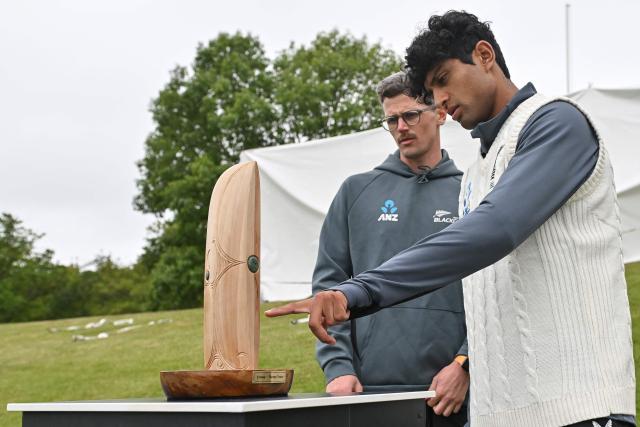 New Zealand's Rachin Ravindra (R) inspects the Crowe-Thorpe trophy, honoring late New Zealand's Martin Crowe and England's Graham Thorpe, two days before the first Test cricket match between England and New Zealand at Hagley Oval in Christchurch on November 26, 2024. (Photo by Sanka Vidanagama / AFP)