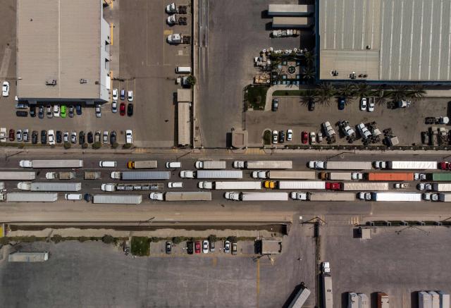 (FILES) Aerial view of cargo trucks lining up to cross to the United States near the US-Mexico border at Otay Mesa crossing port in Tijuana, Baja California state, Mexico, on April 2, 2019. US President-elect Donald Trump said November 25, 2024 he intends to impose sweeping tariffs on goods from Mexico, Canada and China, prompting a swift warning from Beijing that "no one will win a trade war." In a series of posts to his Truth Social account, Trump vowed to hit some of the United States' largest trading partners with duties on all goods entering the country. (Photo by Guillermo Arias / AFP)