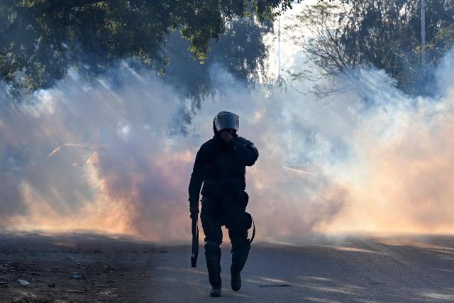 A policeman walks amid tear gas as supporters of Pakistan Tehreek-e-Insaf (PTI) party protest to demand the release of former prime minister Imran Khan, in Islamabad on November 26, 2024. Thousands of protestors calling for the release of Pakistan's jailed ex-prime minister Imran Khan defied roadblocks and tear gas to march to the gates of the nation's capital on November 26. (Photo by Aamir QURESHI / AFP)