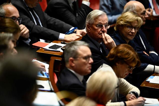 France's Prime Minister Michel Barnier (C) looks on during a session of questions to the government at The National Assembly in Paris, on December 3, 2024. On December 3, 2024, the Conference of Presidents of the National Assembly is expected to decide on the date for the debate and vote on a motion of no confidence, which has every chance of being approved, as the Nouveau Front Populaire (NFP) and the Rassemblement National (RN) have announced that they will vote in its favour. (Photo by JULIEN DE ROSA / AFP)