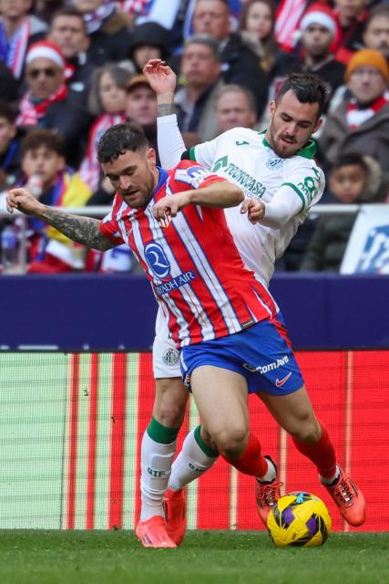 Atletico Madrid's Spanish defender #21 Javi Galan (front) tries to evade Getafe's Spanish defender #07 Alex Sola during the Spanish league football match between Club Atletico de Madrid and Getafe CF at the Metropolitano stadium in Madrid on December 15, 2024. (Photo by Pierre-Philippe MARCOU / AFP)