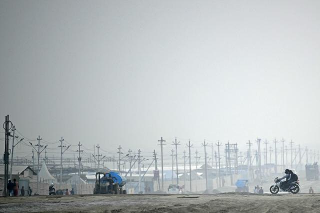 Motorists make their way near the banks of river Ganges, ahead of the Maha Kumbh Mela festival in Prayagraj on December 18, 2024. (Photo by Money SHARMA / AFP)