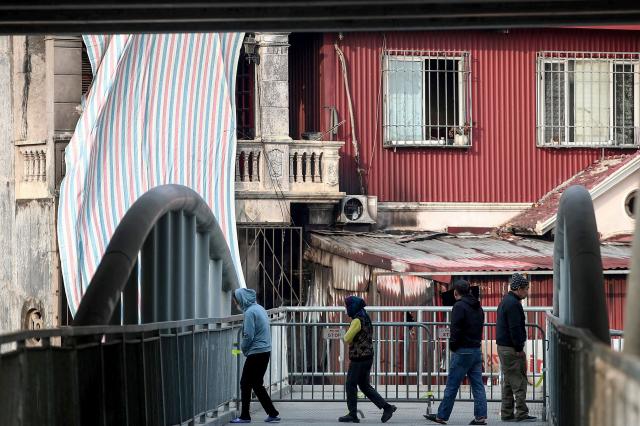 Local residents stand on an overpass outside the scene of a fire at a karaoke bar in Hanoi on December 19, 2024. A fire that ripped through a karaoke bar in the Vietnamese capital killed 11 people and injured two others in a suspected arson attack, police said on December 19. (Photo by Nam NGUYEN / AFP)