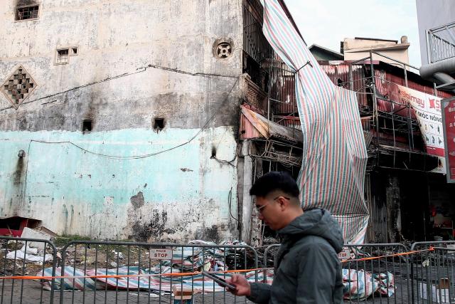 A man uses his phone outside the scene of a fire at a karaoke bar in Hanoi on December 19, 2024. A fire that ripped through a karaoke bar in the Vietnamese capital killed 11 people and injured two others in a suspected arson attack, police said on December 19. (Photo by Nam NGUYEN / AFP)