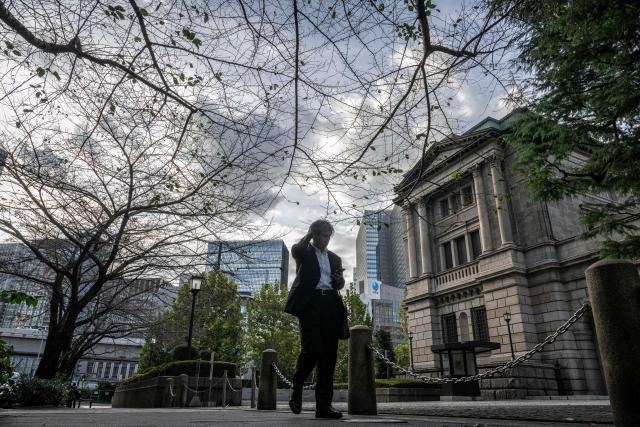 (FILES) This picture taken on October 30, 2024 shows a man walking past the Bank of Japan (BoJ) headquarters in Tokyo. The yen weakened against the dollar on December 19, 2024 after the Bank of Japan kept borrowing costs unchanged, extending a retreat for the currency that came after the US Federal Reserve forecast fewer rate cuts. (Photo by Yuichi YAMAZAKI / AFP)