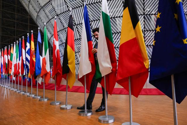 An official adjusts a flag in the lobby of the European Council building in Brussels on December 19, 2024. (Photo by JOHN THYS / AFP)