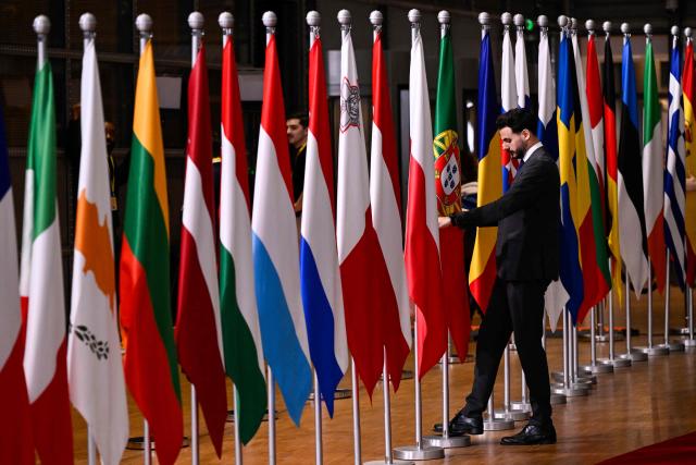 An official adjusts a Portuguese flag in the lobby of the European Council building in Brussels on December 19, 2024. (Photo by JOHN THYS / AFP)