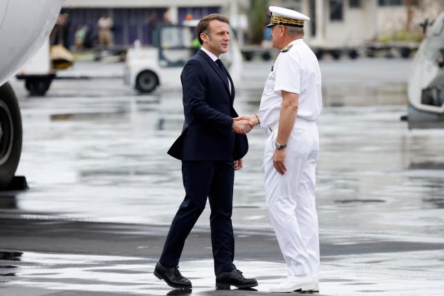 France's President Emmanuel Macron (L) shakes hands with Mayotte's Prefect François-Xavier Bieuville, as he arrives on the tarmac of Dzaoudzi's airport, on the French Indian Ocean territory of Mayotte, on December 19, 2024, following the cyclone Chido's passage over the archipelago. French President Emmanuel Macron on December 19, 2024, arrived in Mayotte to assess the devastation wrought by Cyclone Chido on the Indian Ocean archipelago, as rescuers raced to search for survivors, an AFP journalist said. Macron's plane landed at 10:10 am local time (0710 GMT) with some twenty doctors, nurses and civil security personnel on board, as well as four tonnes of food and sanitary supplies. (Photo by Ludovic MARIN / POOL / AFP)