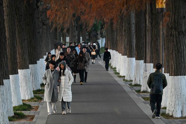 People walk along the East Lake in Wuhan in China's central Hubei province on December 21, 2024, ahead of the fifth anniversary of China confirming its first death from the Covid-19 coronavirus. (Photo by HECTOR RETAMAL / AFP)