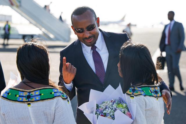 Ethiopian Prime Minister Abiy Ahmed speaks to young inhabitants during the welcoming ceremony of the French President at the Addis Ababa Bole International Airport, in Addis Ababa on December 21, 2024, as part of a two-day visit to Djibouti and Ethiopia. (Photo by Ludovic MARIN / AFP)