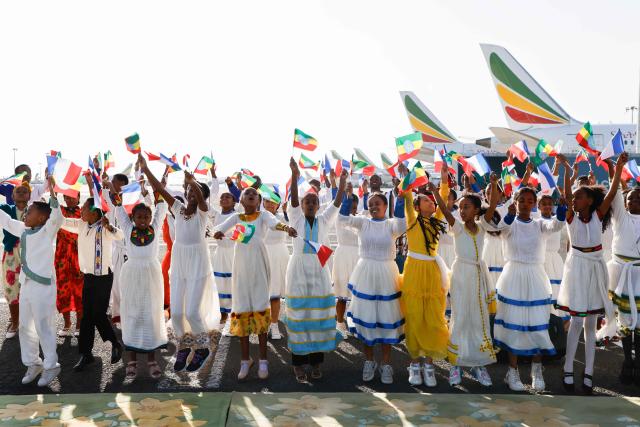 Young inhabitants wave France's national flags and Ethiopia's flags during the welcoming ceremony of the French President at the Addis Ababa Bole International Airport, in Addis Ababa on December 21, 2024, as part of a two-day visit to Djibouti and Ethiopia. (Photo by Ludovic MARIN / AFP)